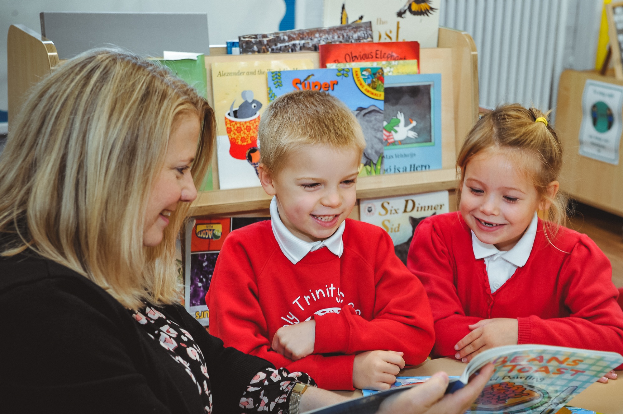 Two students reading with Head Teacher Marie Thompson